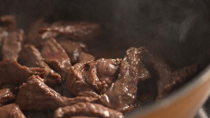 Frying Beef Strips in Pan with steam. Close-up.