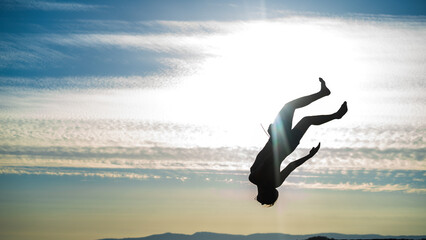 concept about people, lifestyle and sport. A boy performs parkour on the beach. The silhouette...