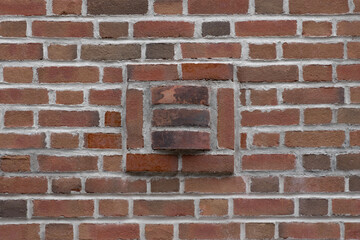 a decorative brick square with extruding custom curved bricks forming a geometric art deco style patttern in a red brickwall laid in flemish bond