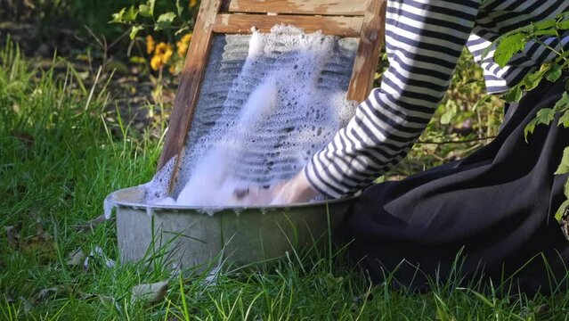 Washing clothes on old vintage washboard outdoors. Antique Washboard. Woman washing on old retro washboard 