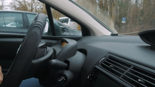 A disabled person parks a car while turning the steering wheel. The car stops.