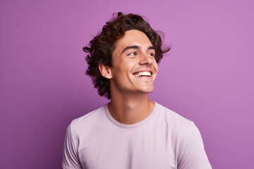 Portrait of happy young man with curly hair, isolated on purple background