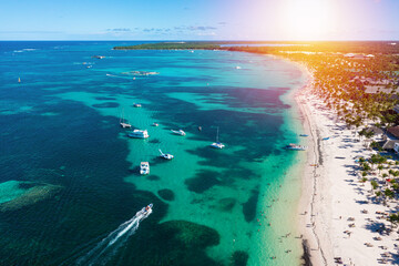 Tropical coastline with resorts, palm trees and caribbean sea with floating boats. Dominican Republic. Aerial view - obrazy, fototapety, plakaty
