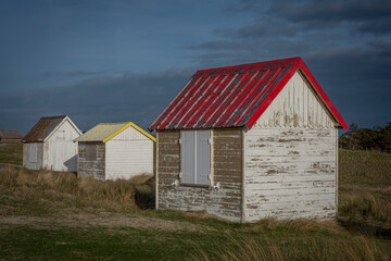 Fototapeta na wymiar Gouville, France - 12 30 2023: View of colorful bathing wooden cabins of Gouville on the dunes.