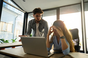 Irritated male boss telling to tense female employee in sunny office