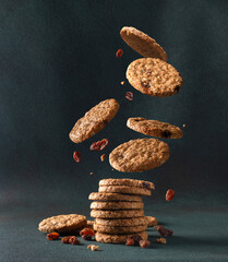 Oatmeal cookies with raisin falling into a stack. Levitating oatmeal cookies on a dark background