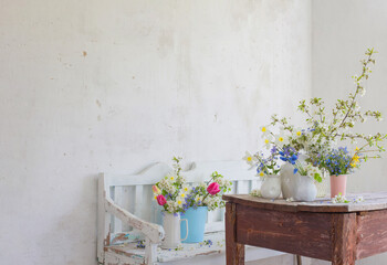 Fototapeta na wymiar spring flowers in vintage white interior with old wooden bench