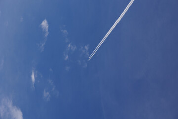 Aereo di linea che viaggia nel cielo azzurro e sereno, visto dal basso mentre lascia la scia di...
