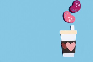 Paper handmade coffee cup with hearts on a pastel blue background. Concept for Valentine's Day, Mother's Day, World Women's Day. Romantic flat composition.
