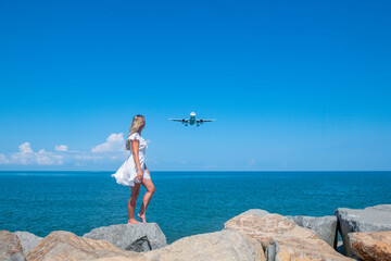 Airborne Encounters: Girl in White Dress on Stones, Plane Over the Blue Sea