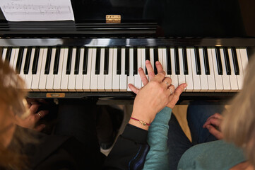 View from above women holding hands, performing classical musical composition, feeling rhythm while play grand piano