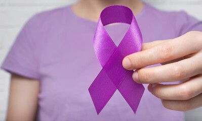 World Cancer Day. A woman holds a purple ribbon in her hand. Anti-cancer tape.