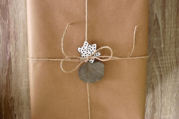 Gift wrapped in recycled paper, decorated with twine, eucalyptus leaf and handmade ornament. Wooden...
