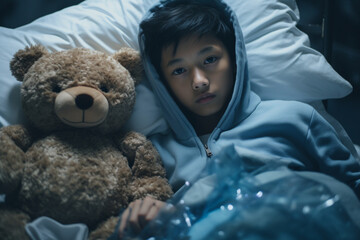 A fifteen year old Asian boy is sick and hospitalised playing with toys in bed
