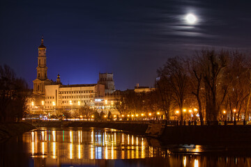 The Lopan River with an embankment and a park in Kharkiv city (Ukraine). Evening cityscape of the city center with buildings and a Christian church