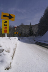 Snow-covered road in the mountain in Japan and road sign.
