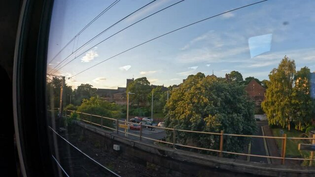 LANCASTER, UNITED KINGDOM, 15 SEPTEMBER 2023: POV: View out the window of a train that has just left the station in Lancaster. A passenger train passes urban environment in beautiful morning light.