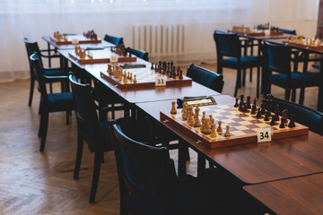 Chess tournament, kids and adults participate in chess match game outdoors in indoor hall, players of all ages play, competition in chess school club with chessboards on a table