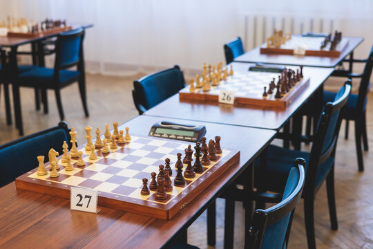 Chess tournament, kids and adults participate in chess match game outdoors in indoor hall, players of all ages play, competition in chess school club with chessboards on a table