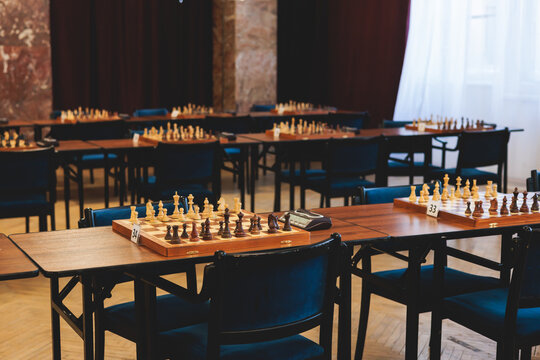 Chess tournament, kids and adults participate in chess match game outdoors in indoor hall, players of all ages play, competition in chess school club with chessboards on a table