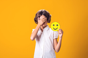 Upset girl holds happy emoticon. Stress and psychology concept - obrazy, fototapety, plakaty
