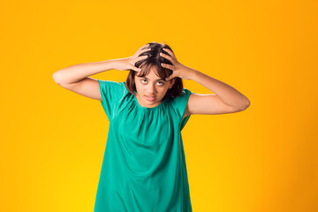 Sad kid girl holding her head over yellow background. Frustration concept