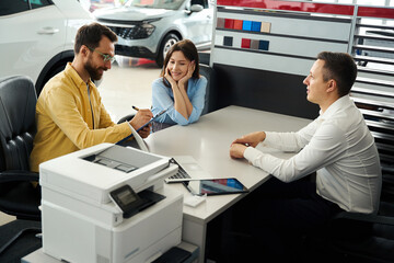 Buyers finalize a deal in office area of car dealership
