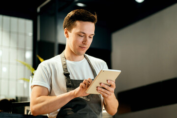 Focused chef using a tablet in a modern kitchen, blending traditional cooking with modern technology.