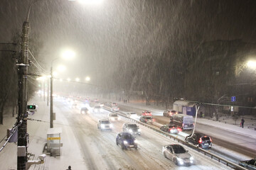 Cars on highway in blizzard. Winter in the city. Traffic jam and traffic camera at night. Cold...