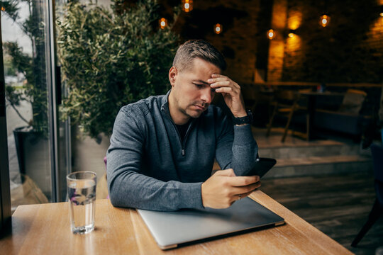 An anxious man is looking at his phone in coffee shop.