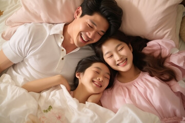 Obraz na płótnie Canvas Happy Asian family lying on bed in bedroom with happy and smile, top view