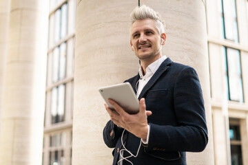 Stylish businessman with tablet outdoors, urban professional on the go.