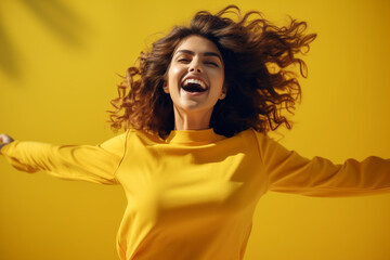 Joyful young woman in yellow shirt jumping and celebrating