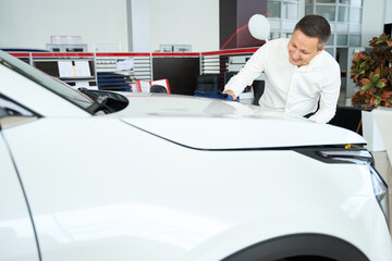 Manager wipes the hood of a car with soft napkin