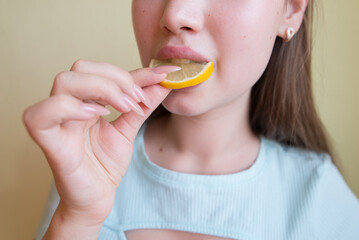 young beautiful girl eating lemon, close-up, crop photo. mouth eating a slice of lemon