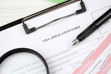 Typical Visa application form on A4 tablet lies on office table with pen and magnifying glass close up