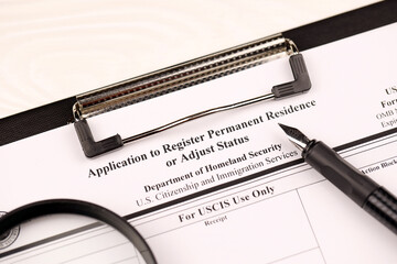 I-485 Application to register permanent residence or adjust status blank, form on A4 tablet lies on office table with pen and magnifying glass close up