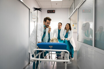 Nurses and doctors in a hurry taking patient to operation theatre. Patient on hospital bed pushed from surgeon and his team to emergency theatre. Team of doctors and surgeon rushing patient. - obrazy, fototapety, plakaty