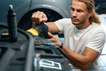 Master in a car repair shop cleans car headlights