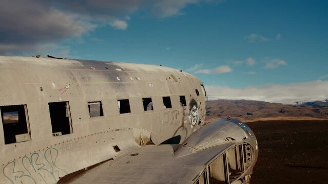 Empty plainwreck from the side, clouds annd mountains in the background