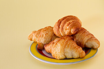 Closeup of some croissants on a plate and with a yellow background