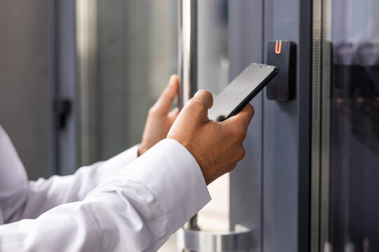 Hand man closely with the phone, the businessman uses the application on the smartphone to remove the door opening of the house, office.