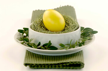 Yellow Easter egg lying on grass in bowl