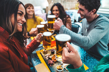 Group of happy friends drinking and clinking beer glasses at brewery bar restaurant - Cheerful millenial people having dinner party sitting in pub garden - Food, beverage and friendship concept - obrazy, fototapety, plakaty