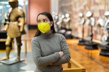 Portrait of interested adult brunette wearing protective face mask visiting exhibition of medieval...