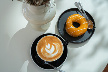Hot coffee latte with latte art milk foam in cup mug and Homemade Orange Donut wood desk on wood...