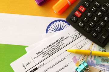 Indian income tax return blank form with pen and indian rupees bills on indian country flag close...