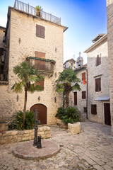 City square with a well pump and stone houses in the historic center of Kotor, Montenegro.