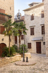 City square with a well pump and stone houses in the historic center of Kotor, Montenegro.