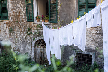 Old stone house in Montenegro with a clothesline with white clothes.